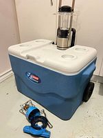 Cooler closed with lantern and stove parts displayed