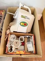 Juicer base in box with control dial visible, attachments alongside