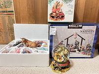 Open styrofoam tray showing porcelain nativity figures, cow, globe with base and both original boxes
