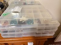 stack of five clear plastic compartment boxes holding assorted beads