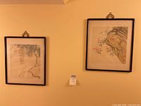 Both framed silk paintings on wall with auction lot tag visible