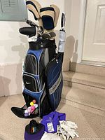 Full view of Nike bag with PowerBilt clubs, headcovers, balls in mesh pouch, gloves and other accessories nearby