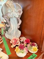 Angel figurine with multiple flower ornaments on shelf