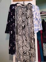 Three garments hanging: abstract maxi dress, floral pajama top, snowman robe