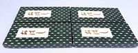 Four closed patterned green boxes with Japanese script labels