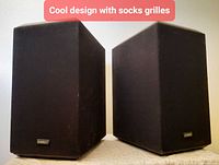 Front view of both Camber 2.0Ti speakers showing wraparound cloth grilles and logo badges