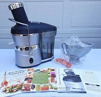 Juicer, container in bag, cleaning brush, manuals displayed