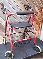 Front view showing red rollator, seat, basket and wheels
