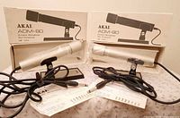 Both microphones in plastic on stands with cables, boxes, manuals visible
