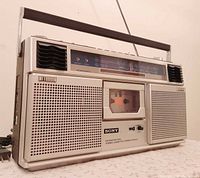 Front angled view showing speakers, cassette deck, tuning scale and handle