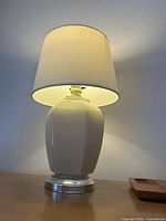 Smaller faceted cream glass lamp illuminated on table