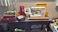 Kenmore sewing machine on cabinet with organisers, lamp and booklet