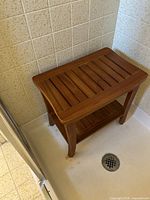 Full view of teak slatted shower bench inside shower stall