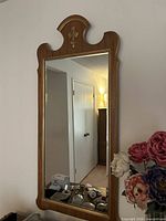 Front view of one mirror showing wood frame, crest, and glass