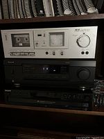 Front view of Akai cassette deck, Sherwood receiver, Sony CD changer stacked on shelf