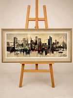 Full view of framed cityscape painting on easel
