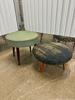 Green and gray ottomans side by side showing upholstery and legs