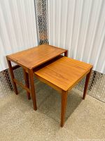 Two rectangular teak nesting tables stacked