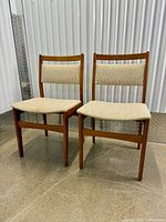 Front view of both teak dining chairs showing upholstery and overall design