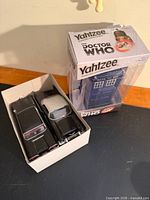 Sealed Doctor Who Yahtzee game beside two die-cast cars in tray
