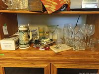 Shelf with beer stein, large martini glass, plates, glasses, accessories