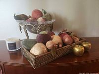 Overview showing glass bowl on metal stand, woven basket with faux fruit and candle