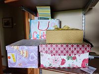 Three decorative boxes and gift bag with bags on shelving