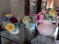 All three porcelain floral figurines on shelf