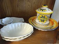 Group view of biscuit jar, matching plates and white scalloped bowls on shelf