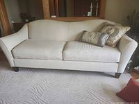Front view of cream two-cushion sofa with two decorative pillows
