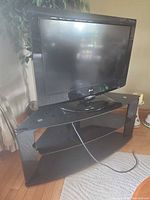 LG flat panel TV sitting on black glass corner stand