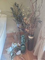 Group of vases, mosaic hurricane and artificial florals arranged on floor