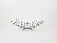 Full side profile of chrome wire grid fruit basket showing curved form and ball feet