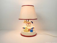 Full view of lit rocking horse nursery lamp showing shade and base