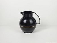 Front view of black spherical carafe showing gold stripe and handle