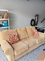 Front view of soft gold 3-seat sofa with two accent pillows