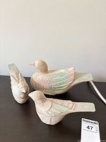 Front view of three carved painted wood birds