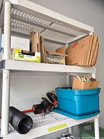 Shelf with garden bags, clear recycling bags, blue tote, hedge trimmer, charger, black pipe