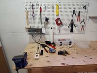 Overall view of bench with vise, radio, levels, screwdrivers, pliers on pegboard