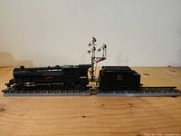 Locomotive, tender, two track pieces and metal signal arranged on wood surface