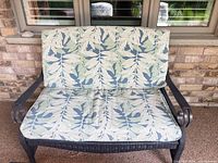 Front view of Hampton Bay resin wicker loveseat with leaf-patterned cushions
