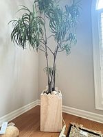 Planter with faux tree and rocks in corner of room