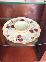 Top view of stoneware serving dip plate showing scalloped rim, central dip bowl and hand-painted motif