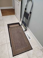 Step stool folded leaning against wall next to two stacked mats on tiled floor