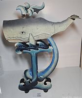 Front view of metal sperm whale sky hook sculpture on wave stand