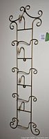 Full view of vertical brass rack showing all four tiers and scrollwork ends