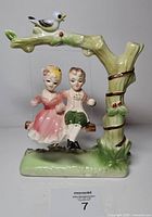 Front view showing couple on swing, tree trunk, bird on branch