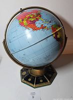 Front view of tin globe showing North America, meridian and base