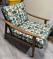 front angled view of chair showing teak frame and patterned cushions