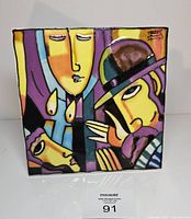 Front of cubist glazed ceramic tile showing abstract figures, candles, signature visible